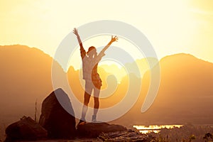 Happy slim girl with raised arms against sunrise or sunset sea