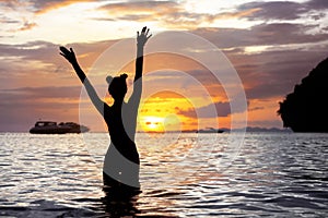Happy slim girl raised arms sunset sea beach