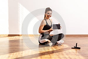 Happy slim woman holding tablet with blank screen, showing sports application for online training.