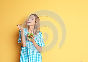 Happy slim woman with salad on color background.