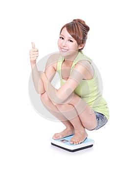 Happy slim woman with scales and show thumb up