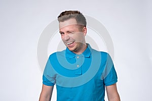 Happy sly man in blue t-shirt winking an eye