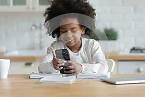 Happy small african ethnicity biracial child involved in mobile game.