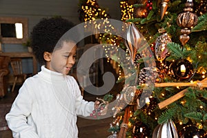 Happy small biracial kid decorate Christmas tree