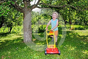 Happy small boy help with gardening with his lawn mower