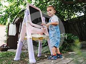 Happy small boy playing on playground. Playful child outdoor activity.