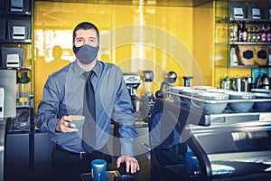 Happy small business owner with protective face mask serving coffee behind counter after store reopening