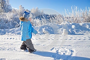 Happy small child the boy on walk in the winter in park