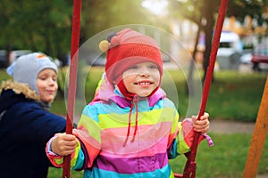 Happy Small children roll each other on swing. Children playing on the carousel. Children playground