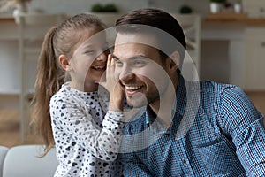 Happy small cute child girl telling secret to daddy. photo