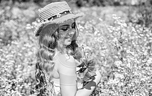 Happy small girl with beauty look wear sun hat on long curly blonde hair holding poppy flowers on natural sunny summer