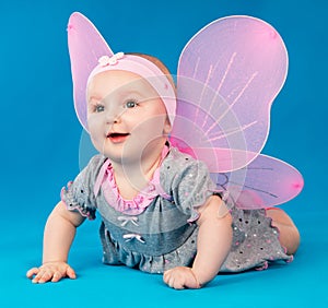 Happy small girl butterfly wings sitting on the floor