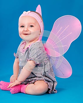 Happy small girl butterfly wings sitting on the floor