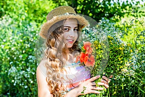 Happy small girl collecting poppy flowers sunny day nature background