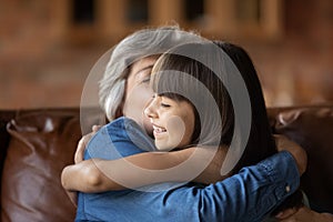 Happy small girl hug mature grandmother at home