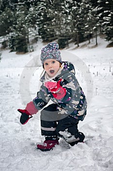 Happy small girl playing with snow in nature