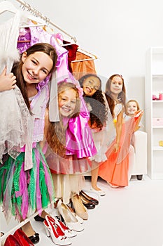 Happy small girls in store standing among dresses