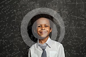 Happy smart black child student on blackboard background with science and maths formulas