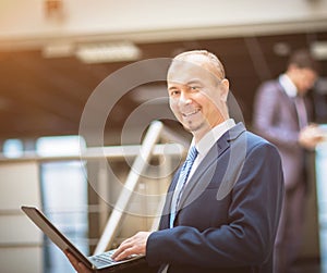 Happy smart business man with a laptop in hand on the background of team
