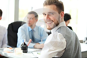 Happy smart business man with team mates discussing in the background.