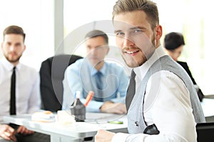 Happy smart business man with team mates discussing in the background.