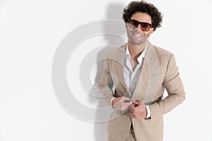 happy smart casual man laughing and unbuttoning beige suit