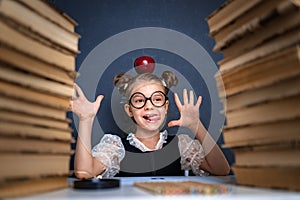 Happy smart girl in rounded glasses with red apple on her head s