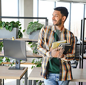 Happy smart indian or arabian guy, mixed race male, university student, stands in the library against the background of