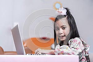Happy / smile Asean girl using laptop computer to study online e-learning from living room decorate party holiday at home