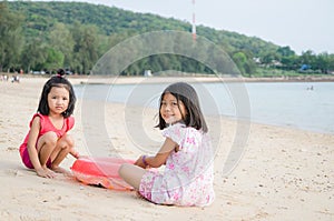 Happy smile asian kids girl Thai child playing sand on the beac photo