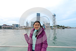 happy smile Asian tourist woman standing on boat taking portrait picture with scenic view of Batumi, Georgia and landmarks during