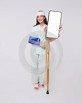 Happy smile asian woman patient put on a cast showing smartphone mockup of blank screen for application insurance and healthcare