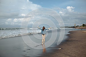 Happy smile brunette Woman wearing black swimsuit and denim jacket at ocean background enjoy walking at beach, hands