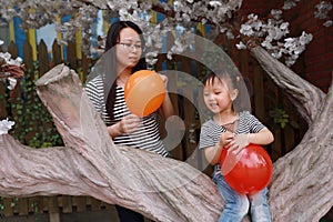 Happy smile child with mother mom and daughter play balloon outdoor family parental activity joyful childhood summer