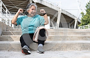 Happy and smile elderly asian woman sitting on stairs for rest after workout, jogging on morning, senior exercise outdoor for good