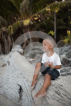 Happy smile european blond baby boy have rest and sit on white sand beach