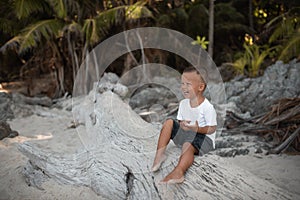 Happy smile european blond baby boy have rest and sit on white sand beach