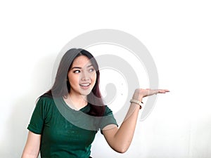 Happy and smile face with smile of young Asian girl in green shirt with hand point on empty space