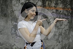 Happy and smile face with smile of young Asian girl with hand point on empty space