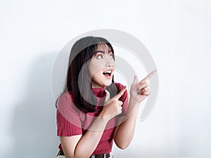 Happy and smile face with smile of young Asian girl in red shirt with hand point on empty space