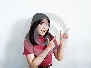 Happy and smile face with smile of young Asian girl in red shirt with hand point on empty space