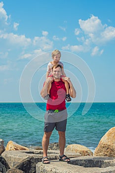 Happy smile father hugs holds on shoulders boy male child stand blue lazur sea panorama skyline horizon sunshine day