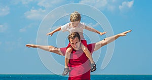 Happy smile father hugs holds on shoulders son boy male child stand blue lazur sea panorama skyline horizon in sunshine photo