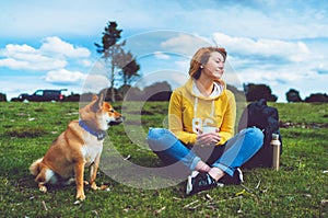 Happy smile girl holding in hands cup drink, red japanese dog shiba inu on green grass in outdoors nature park, beautiful young
