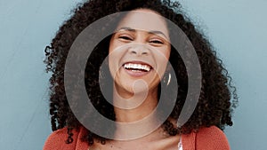Happy, smile and laugh with the face and head of an attractive black woman smiling on a gray background or wall. Closeup