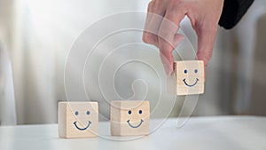 A happy smile is painted on the face of a wooden block cube to symbolize optimism. notion of emotional and mental wellness
