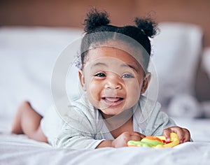 Happy, smile and portrait of a baby on a bed playing with a toy while relaxing in her nursery. Happiness, excited and