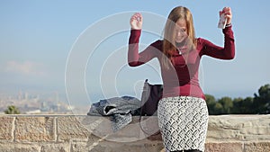 Happy smileing girl look at camera and dance sitting on the border wall