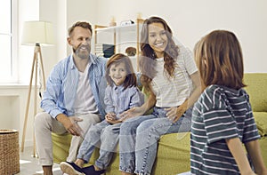 Happy smiley young mother, father and their little children all together at home