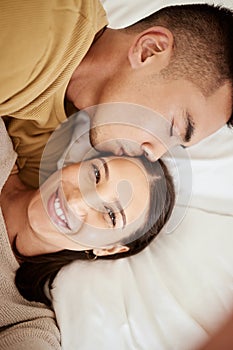 Happy, smiling and affectionate young couple in love taking a selfie together in the bed at home. Portrait of loving